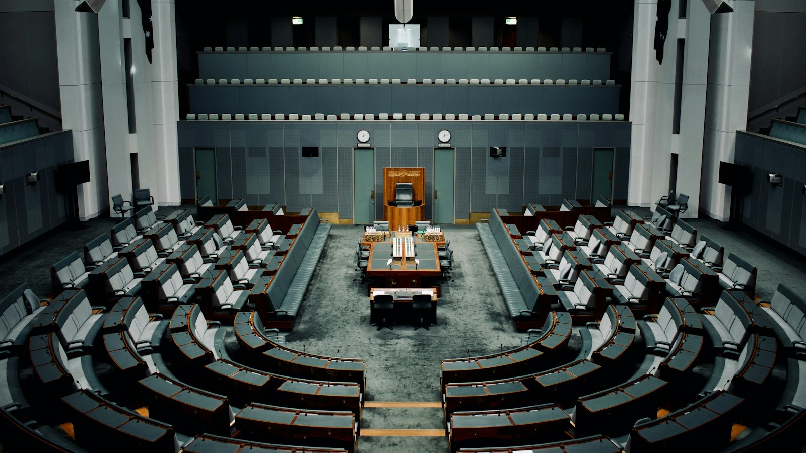 An empty parliamentary chamber with rows of seats facing the speaker, standing for the governments whose decisions shape the value of carbon credits